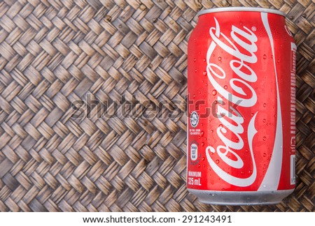 PUTRAJAYA, MALAYSIA - JUNE 28TH, 2015. Coca Cola can on wicker background. Coca Cola drinks are produced and manufactured by The Coca-Cola Company, an American multinational beverage corporation.