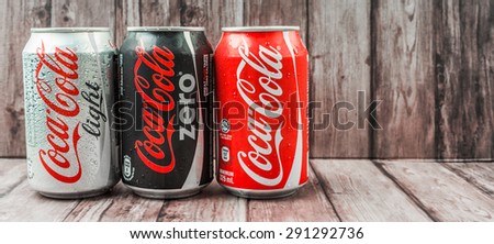 PUTRAJAYA, MALAYSIA - JUNE 28TH, 2015. Coca Cola cans on weathered wood. Coca Cola drinks are produced and manufactured by The Coca-Cola Company, an American multinational beverage corporation.