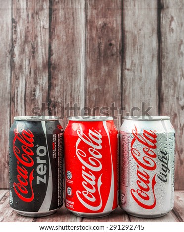PUTRAJAYA, MALAYSIA - JUNE 28TH, 2015. Coca Cola cans on weathered wood. Coca Cola drinks are produced and manufactured by The Coca-Cola Company, an American multinational beverage corporation.