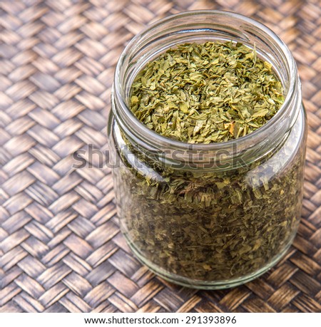 Dried parsley herbs in a mason jar over wicker background