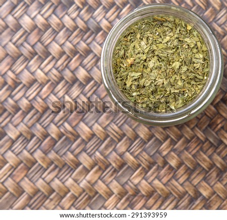 Dried parsley herbs in a mason jar over wicker background