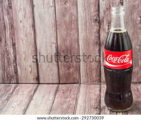 PUTRAJAYA, MALAYSIA - JULY 2ND, 2015. Coca Cola bottle on weathered wood. Coca Cola drinks are produced and manufactured by The Coca-Cola Company, an American multinational beverage corporation.