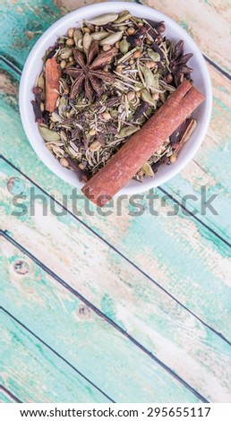 Mix herbs and spices in white bowl over aged wooden background