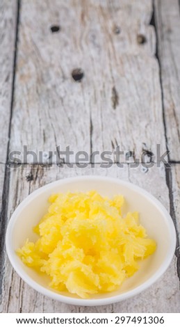 A bowl of Indian ghee in white bowl over wooden background