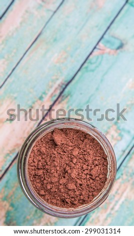Brown pure cocoa powder in a mason jar over rustic wooden background