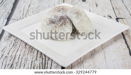 Japanese confection, round glutinous rice stuffed with sweetened red bean paste or locally known as daifukumochi in a white plate over wooden background
