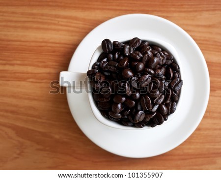 coffee beans with white coffee cup on wood texture.( selective focus )