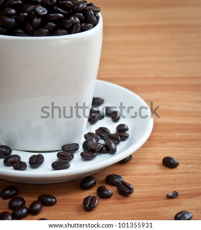 coffee beans with white coffee cup on wood texture.( selective focus )