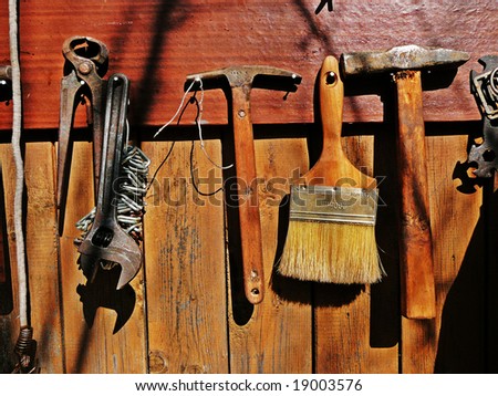 old tools, paint brush & hammers on wooden wall