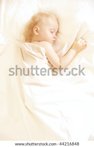 a sweet little child sleeping on a white bed sheets, space for text