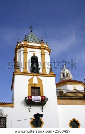 Detail of Christian church in Ronda Spain showing banner and bell tower against blue sky