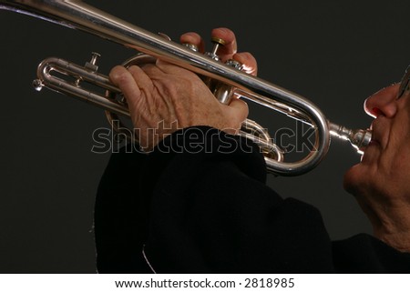 Man plays silver trumpet with back-lighting