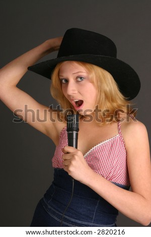 Teenage girl in country western outfit sings with microphone