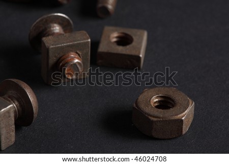 Macro view collection of old rusted nuts and machine screws on a black background