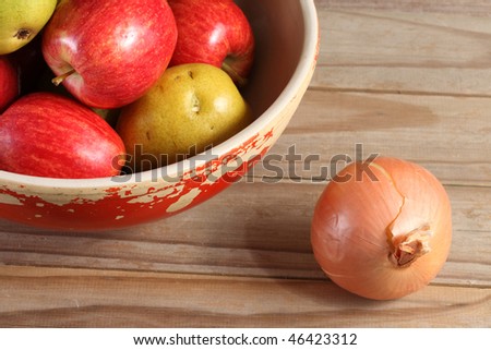 Anjou pears and Gala apples in a chipped painted bowl with a whole yellow onion on a weathered wooden plank deck