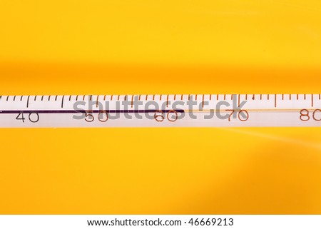 Macro view of a liquid column photography laboratory thermometer against a yellow background