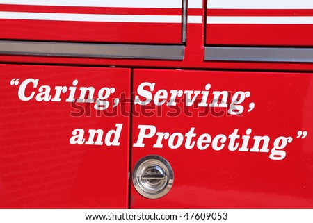 Lettered sign caring serving and protecting in bold white letters on the side of a red emergency vehicle