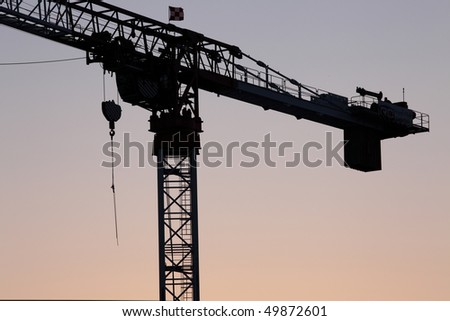 Hammerhead crane at a construction site silhouetted against the sky at sunset