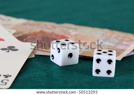 Playing cards dice and two bills of Moroccan currency on a green gaming table