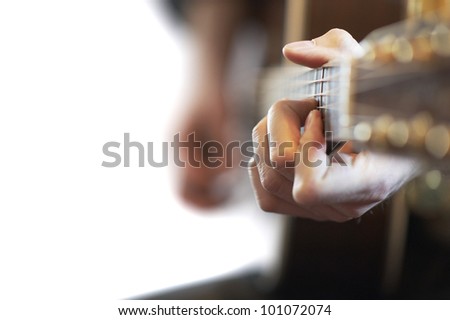 Bright side view of an acoustic western guitar with player and shallow depth of field