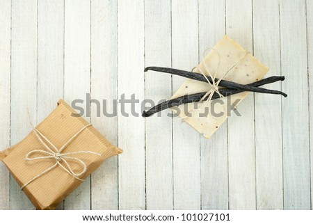 natural soap with vanilla beans and wrapped gift box, bright wooden background