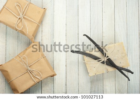 natural soap with vanilla beans and wrapped gift box, bright wooden background