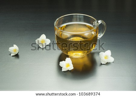 cup of jasmine tea with jasmine flowers on black wooden table