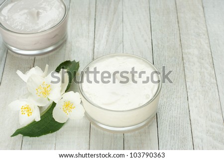 face and body cream moisturizers with jasmine flowers on white wooden, top view