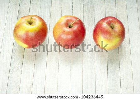 three apples on white wooden table