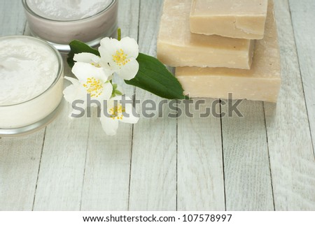 face and body cream moisturizers with jasmine flowers on white wooden, top view