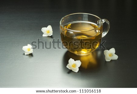 cup of jasmine tea with jasmine flowers on black wooden table