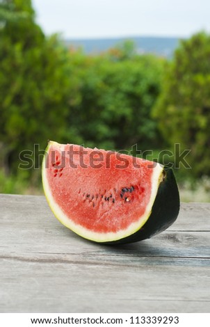 slice of watermelon on wooden table, mediterranean garden background