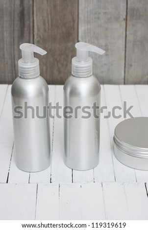 brushed aluminum cosmetic bottles with pump and cream jar on wooden