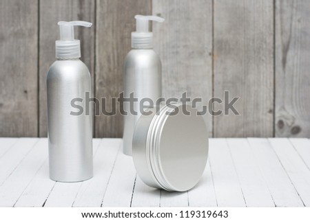 brushed aluminum cosmetic bottles with pump and cream jar on wooden