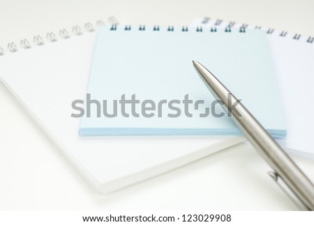 empty notebooks with pen on white office table, focus on pen, shallow depth of field
