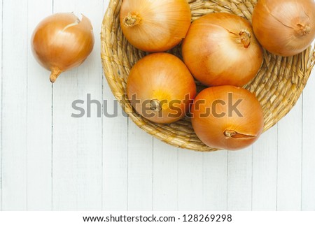 red onions in rustic bowl directly above, white wood table background
