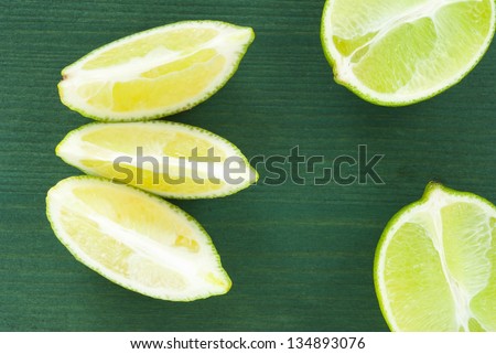 lime slices and half cut lime on green wood table background, top view