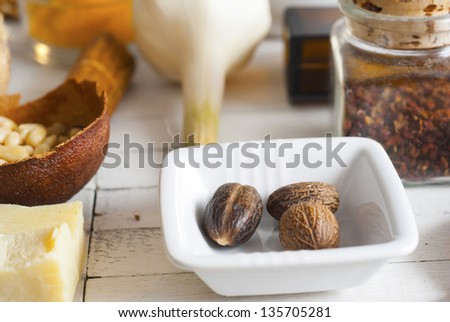nutmegs, herbs and spices on white wood table