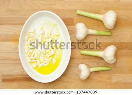 sliced garlics on extra virgin olive oil, wooden table, directly above