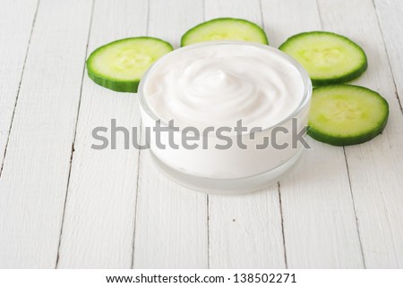face mask with cucumber slices, white wood background