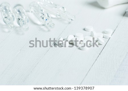 hypodermic needles and pills, white wooden background