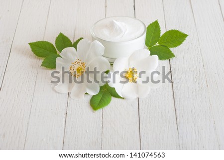 moisturizer cream with field roses on white wooden