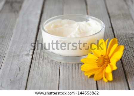 cosmetic cream with herbal flower on rustic wooden table