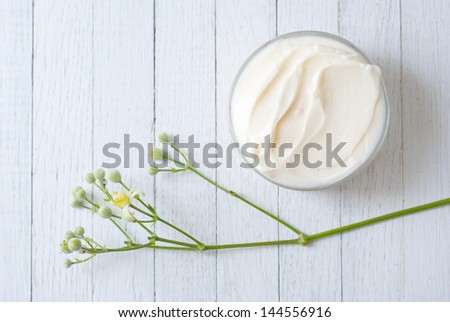 cosmetic cream with herbal flowers on white wood table