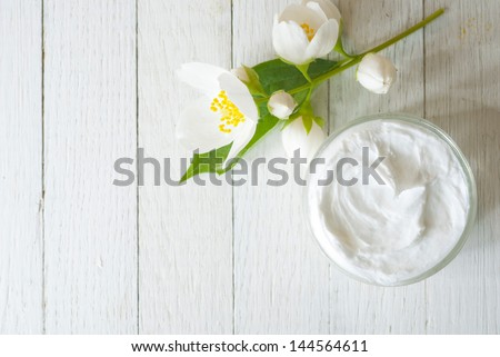face cream with jasmine blossom on white wooden table