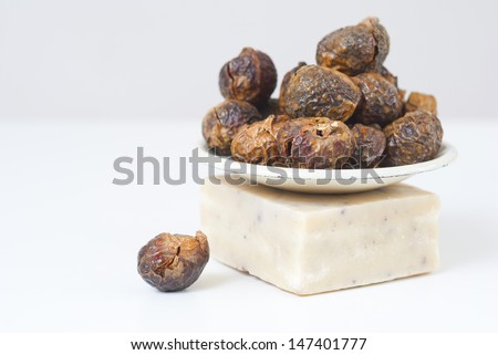 a pile of soap nuts on little metal plate, on a block of natural lavender soap