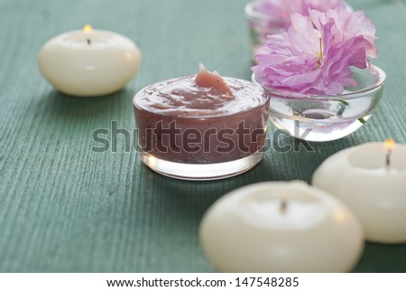 spa setting with cosmetics, candles and japanese cherry blossoms, wood table background