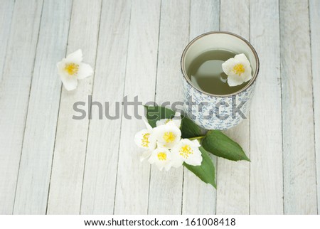 jasmine tea and jasmine flowers on white wooden background, top view