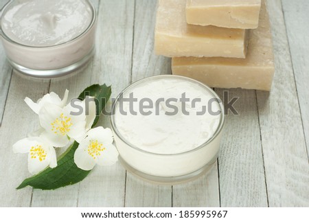 face and body cream moisturizers with jasmine flowers on white wooden