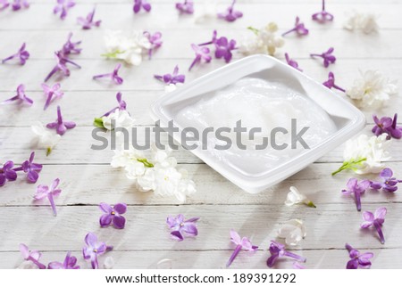 cosmetic cream with flowers on white wood table